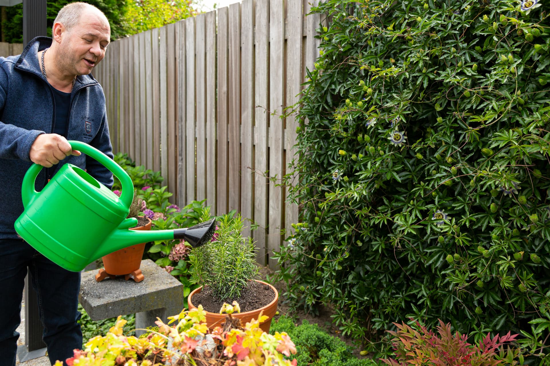 Bewoner geeft planten water in de tuin