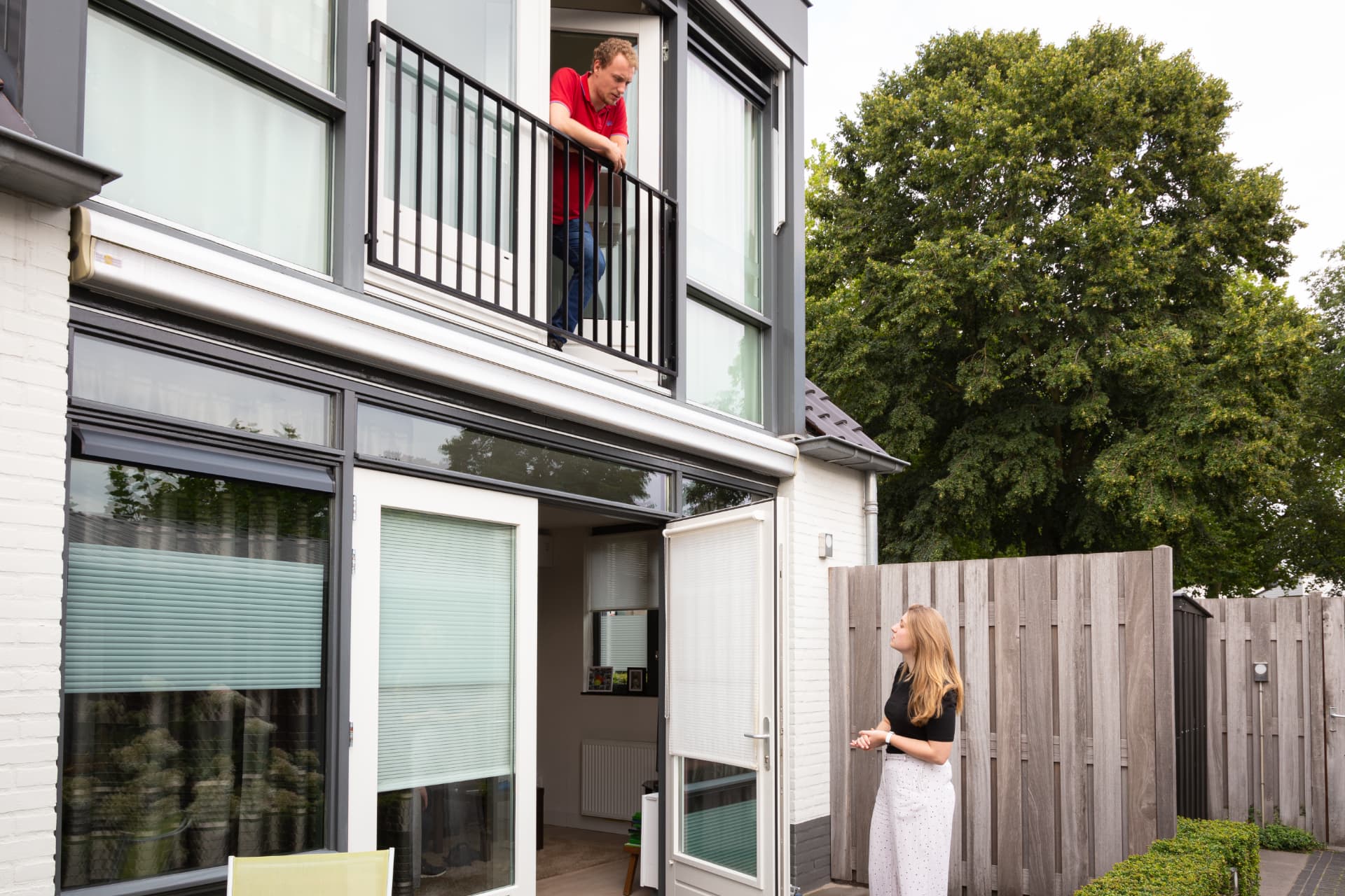 Bewoner op balkon in gesprek met medebewoner